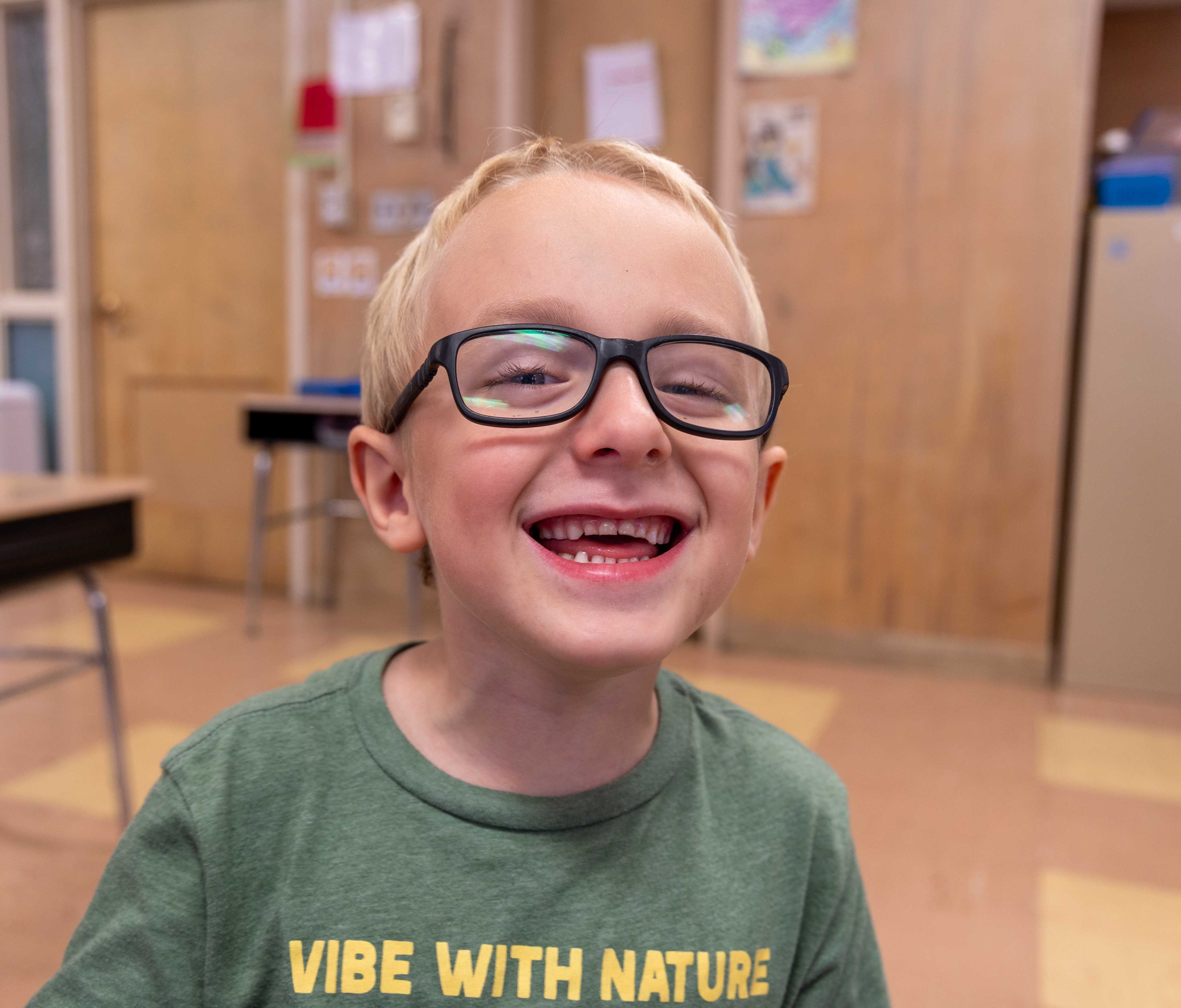 a young student with glasses smiles brightly